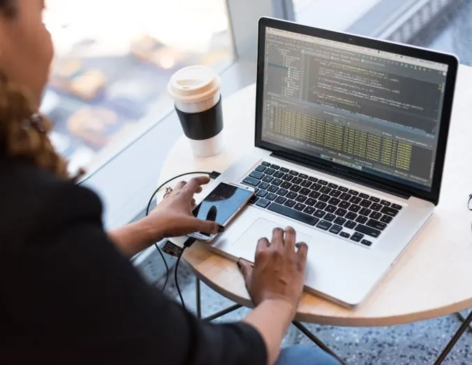 Un profesional experto se encuentra trabajando en su computadora portátil, con códigos visibles en la pantalla. Junto a él hay un teléfono inteligente y una taza de café sobre la mesa, reflejando un escenario típico de trabajo moderno. Esta imagen simboliza perfectamente cómo el entorno laboral actual está dominado por la tecnología digital y las prácticas innovadoras. Este tipo de conjuntos de trabajo están diseñados para maximizar la eficiencia y el rendimiento optimizando tanto el tiempo como los recursos disponibles.